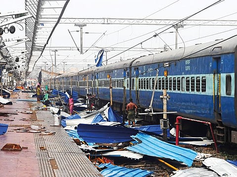 People collect debris on the train tracks at the damaged railway station in Puri in the eastern Indian state of Odisha on May 4, 2019, after Cyclone Fani swept through the area.