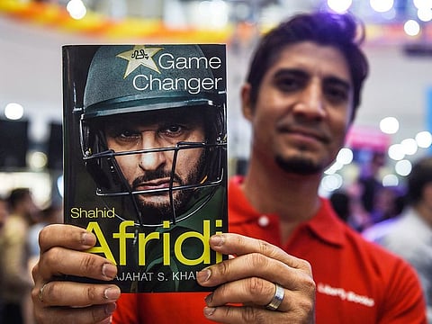 A cricket fan holds Shahid Afridi's autobiography as he came for a press conference to present the book in Karachi on May 4, 2019.