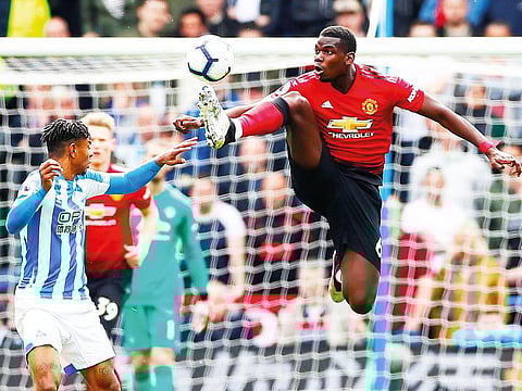Manchester United’s Paul Pogba jumps to grab control as Huddersfield’s Juninho Bacuna watches on on Sunday.