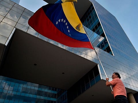 An anti-government demonstrator waves a Venezuelan national flag in front of the Parque Cristal building in eastern Caracas during a day of vigils and prayers called by opposition leader and self-proclaimed interim president Juan Guaido, on May 5, 2019.
