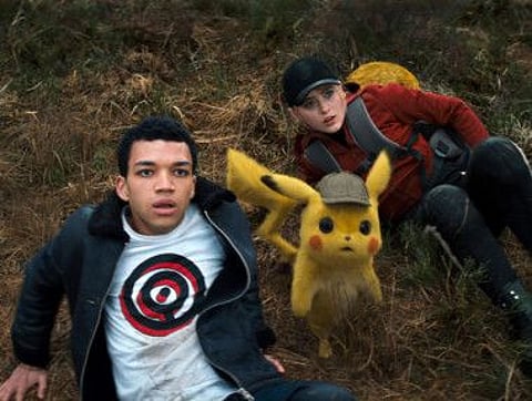 This image released by Warner Bros. Pictures shows Justice Smith, left, the character Detective Pikachu, voiced by Ryan Reynolds, and Kathryn Newton in a scene from "Pokemon Detective Pikachu." (Warner Bros. Pictures via AP)