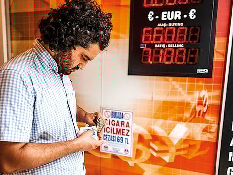 A man counts banknotes at an exchange bureau in Istanbul, Turkey. The replacement of Turkey's central bank governor undermines the credibility of the country's monetary policy warned Scope Ratings.