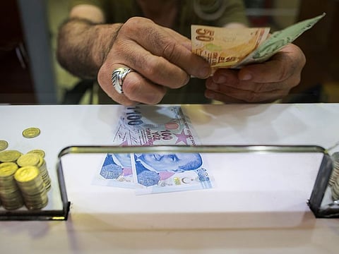 A cashier counts out Turkish lira banknotes on the counter of a foreign currency exchange store in Istanbul, Turkey.