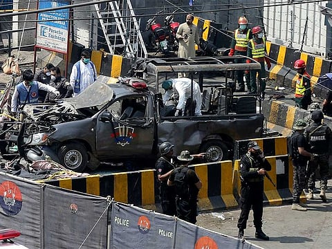 Pakistani security personnel surround the targeted police van in Lahore, Pakistan, Wednesday, after a suicide bomb outside the gate of famous Sufi shrine of Data Darbar in Lahore on Wednesday