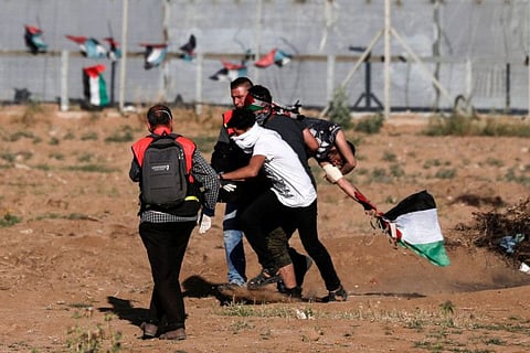 Palestinian paramedics carry an injured protester during clashes with Israeli forces following a demonstration by the border fence with Israel, east of Gaza City, on May 3, 3019.