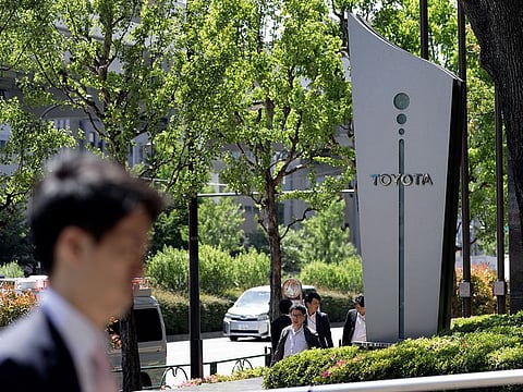 Pedestrians walk past signage for Toyota Motor Corp. displayed outside the company's offices in Tokyo, Japan.