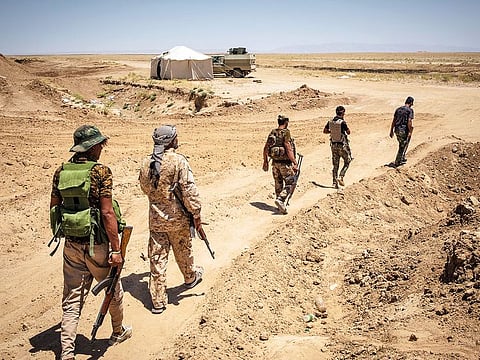 Members of Popular Mobilisation Forces, an Iraqi state-sponsored umbrella organisation walk at their positions outside Al Badi, Iraq.