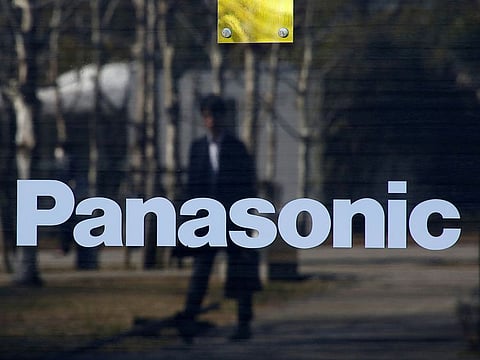 A man is reflected on Panasonic Corp's logo at Panasonic Center in Tokyo, Japan.