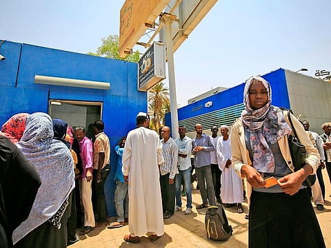 Sudanese people queue up to withdraw money from an ATM in Sudan's capital Khartoum on May 9, 2019.