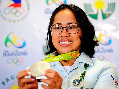 In this file photo taken on August 11, 2016, Philippine silver medallist at the Rio Olympics, Hidilyn Diaz shows her medal during a press conference as she arrives at the Manila International Airport in Manila