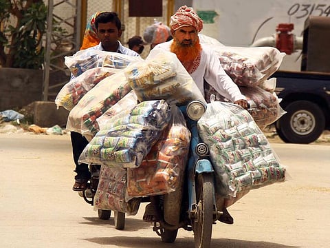 A supplier of children’s items carries huge plastic packets of snacks, going to supply shop to shop to earn for his livelihood.