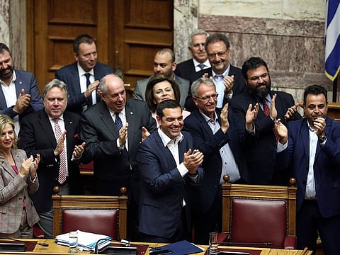 Greece's Prime Minister Alexis Tsipras, center, and his lawmakers applaud after a parliamentary session where the government won a confidence vote, in Athens, on Friday, May 10, 2019.