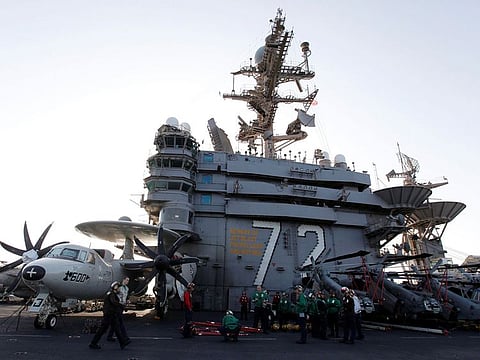 Flight deck personnel stand on the flight deck on board the Nimitz-class aircraft carrier USS Abraham Lincoln (CVN 72) as it patrols the Arabian Gulf during a Strait of Hormuz transit