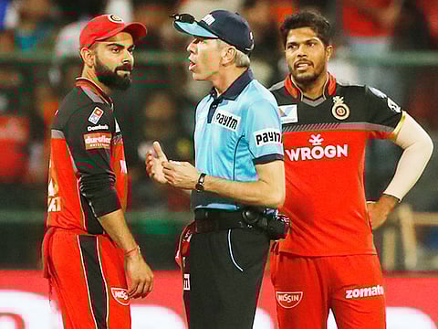 Royal Challengers Bangalore captain Virat Kohli, left, interacts with the umpire, center, as teammate Umesh Yadav, right, watches during the VIVO IPL T20 cricket match between Royal Challengers Bangalore and Sunrisers Hyderabad in Bangalore, on Saturday, May 4, 2019.