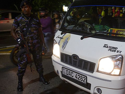 A Sri Lankan security officer looks on as he stands guard at a checkpoint on a roadside in Colombo on May 13, 2019.