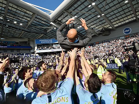 Manchester City's manager Pep Guardiola is thrown into the air by his players as they celebrate after their 4-1 victory in the English Premier League football match against Brighton and Hove Albion at the American Express Community Stadium in Brighton, southern England on May 12, 2019.