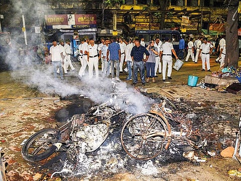 Police personnel look on near vehicles burnt by a mob during BJP President Amit Shah's election roadshow for the last phase of Lok Sabha polls, in Kolkata, Tuesday, May 14, 2019.