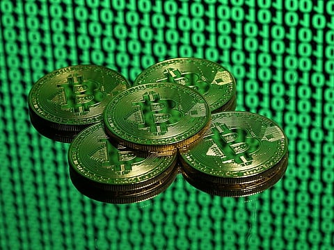 Tokens of the virtual currency Bitcoin are seen placed on a monitor that displays binary digits.