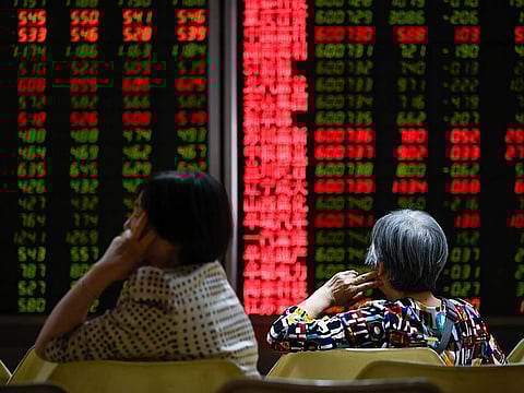 Investors rest on a chair in front of screens showing stock market movements at a securities company in Beijing.