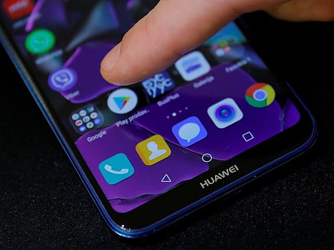 A man points a finger to the Google Play app logo on his Huawei smartphone.