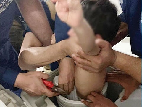 Firemen struggle to retrieve the boy from the washing machine.