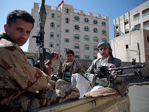 An April 19, 2017 file photo of Shiite fighters, also known as Houthis, securing a road, as people take part in a march from Sanaa to the port city of Hodeidah, Yemen.
