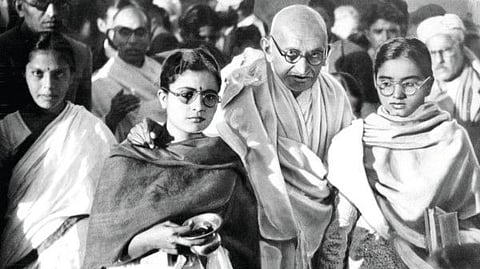File photo of January 1948: Mahatma Gandhi resting arms on shoulders of two disciples.