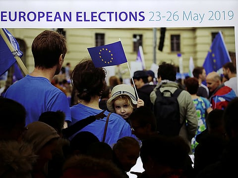 People walk past a screen displaying an advertisement for the EU elections at the European Parliament in Brussels,