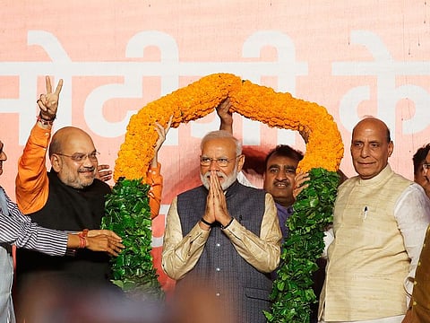 BJP President Amit Shah, left, and Home Minister Rajnath Singh, right, present a giant floral garland to Prime Minister Narendra Modi at the party headquarters in New Delhi.