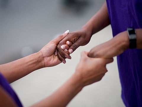People pray outside Ramoneros Liquor and Bar in Trenton, N.J. where at least nine people were wounded by gunfire sprayed into a crowd outside it early Saturday morning, May 25, 2019.