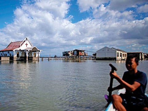 This photo taken on January 11, 2019 shows a man rowing past a chapel amid encroaching bay waters in Sitio Pariahan, Bulacan.