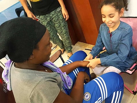 Moroccan expat Sara Khaled (8) gives a hand massage to a worker - all in the spirit of Ramadan