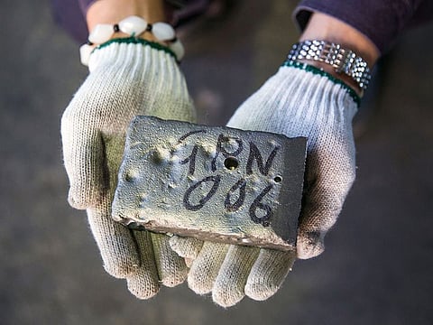 A worker holds an ingot of a rare earth metal used to make components for technology products at a factory in Tianjin, China.