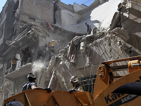 White helmet rescue volunteers and civilians search for survivors amidst the rubble of a building destroyed during an air strike by Syrian regime forces and their allies on the town of Ariha, in the southern outskirts of Syria's Idlib province on May 27, 2019.