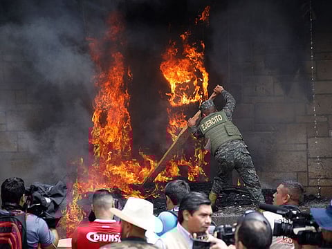 A soldier works to put out a tire fire started by protesters outside the main entrance into the U.S. Embassy during a protest against the government of President Juan Orlando Hernandez, in Tegucigalpa, Honduras, Friday, May 31, 2019.