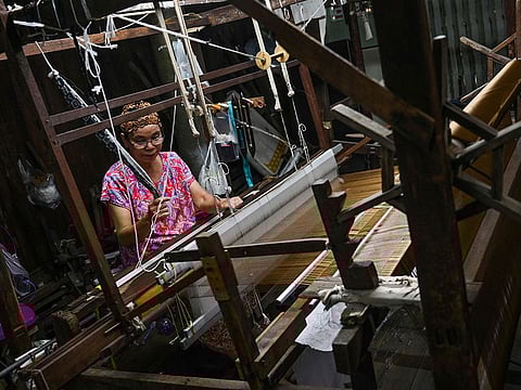 Rampai Sripetch, a 65-year-old Thai Muslim woman, weaving silk fabric on a loom at a workshop near Darul Falah mosque in Bangkok.