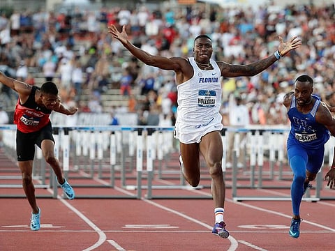 Florida's Grant Holloway, center, raises his arms as he wins the men's 110 meter hurdles finals during the NCAA outdoor track and field championships in Austin, Texas, Friday, June 7, 2019.