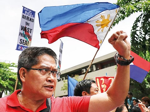 A protester raises his fist beside a national flag during a protest outside the Chinese Consulate in the financial district of Makati, metropolitan Manila, Philippines to mark Independence Day on Wednesday, June 12, 2019.