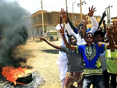 Sudanese protesters gesture and chant slogans at a barricade along a street, demanding that the country's Transitional Military Council hand over power to civilians, in Khartoum, Sudan.