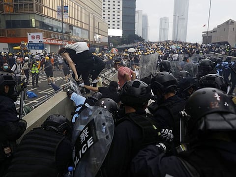 Riot police follow protesters over a median barrier near the Central Government Offices during a protest against a proposed extradition law in Hong Kong