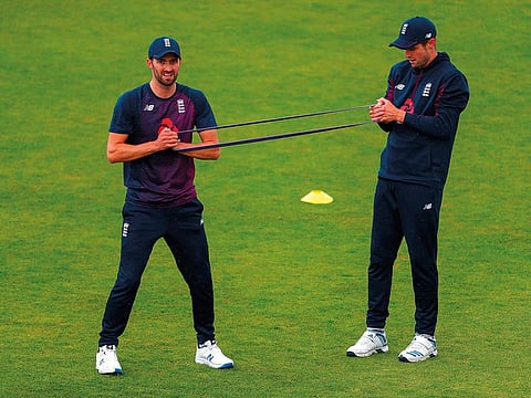 England's Mark Wood (L) and Chris Woakes use a stretching band during a training session at the Rose Bowl in Southampton, southern England on June 13, 2019, ahead of their 2019 Cricket World Cup group stage match against West Indies.