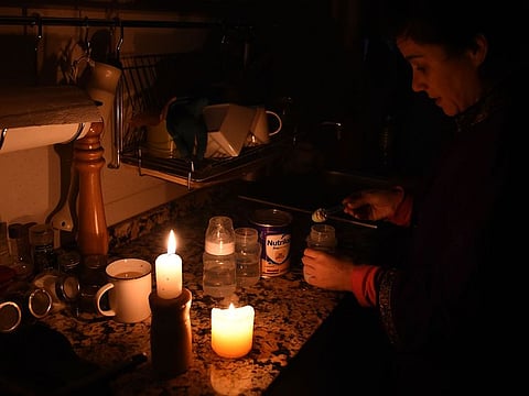 A woman prepares milk bottles using candles at her home in Montevideo during a power cut.
