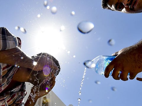 Man washes his face to cool down during the afternoon hours of hot weather in Sharjah Industrial area.