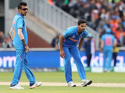 India's Bhuvneshwar Kumar, right, bends in pain after bowling.