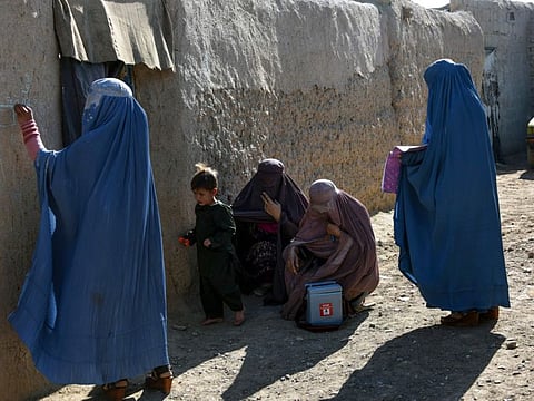 Afghan women from a polio immunisation team write on the wall of a house where residents are absent to ensure they will be vaccinated later, in Kandahar province's Arghandab district.