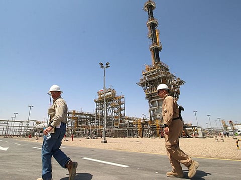 A member of security foreign personnel walks with an Exxon's foreign staff of the West Qurna-1 oilfield, which is operated by ExxonMobil, during the opening ceremony near Basra