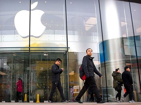 People walk past an Apple store at an outdoor shopping street in Beijing