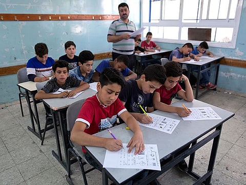 A teacher supervises while Palestinian school children attend a final exam during the last day of the school year, at the United Nations Relief and Works Agency for Palestine Refugees in the Near East, UNRWA, Hebron Boys School, in the West Bank city of Hebron.