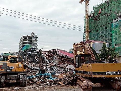 Rescue workers use earthmovers to clear debris after a building collapsed at a construction site in Sihanoukville on June 22, 2019.