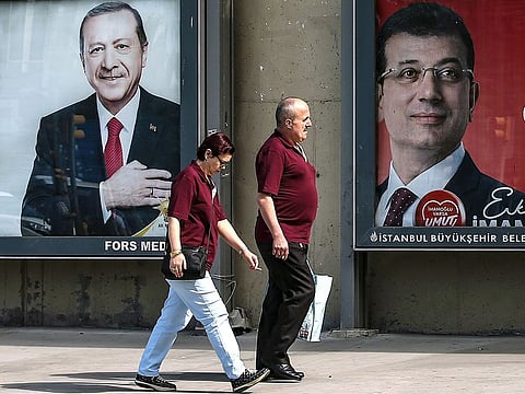 People walk past posters of Turkey's President Recep Tayyip Erdogan, left, and Ekrem Imamoglu, right, Istanbul's mayoral candidate of the secular opposition Republican People's Party, or CHP, ahead of June 23 re-run of Istanbul elections, in Istanbul.